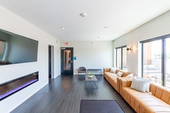 A modern living room with a long couch and a flat screen TV.at Rowat Lofts, Iowa, 50309
